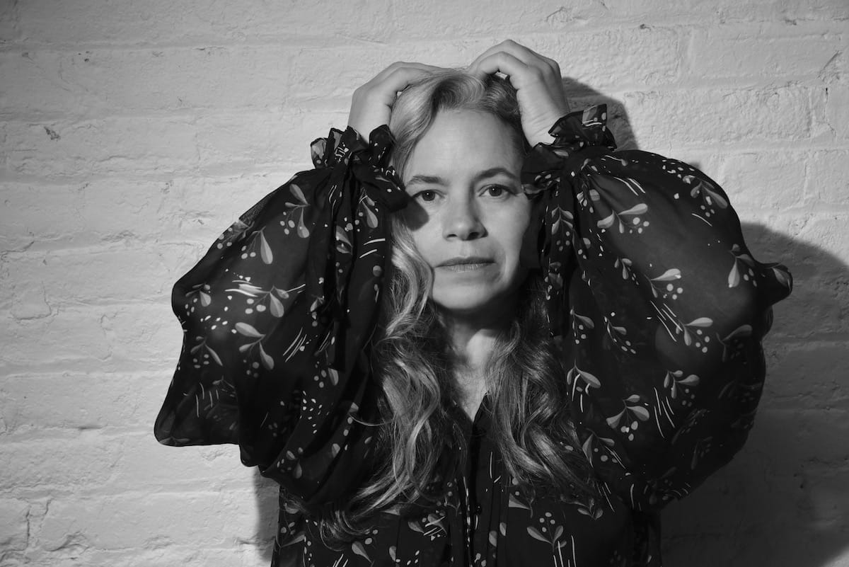 A black and white photo of Natalie Merchant with her hands on her head