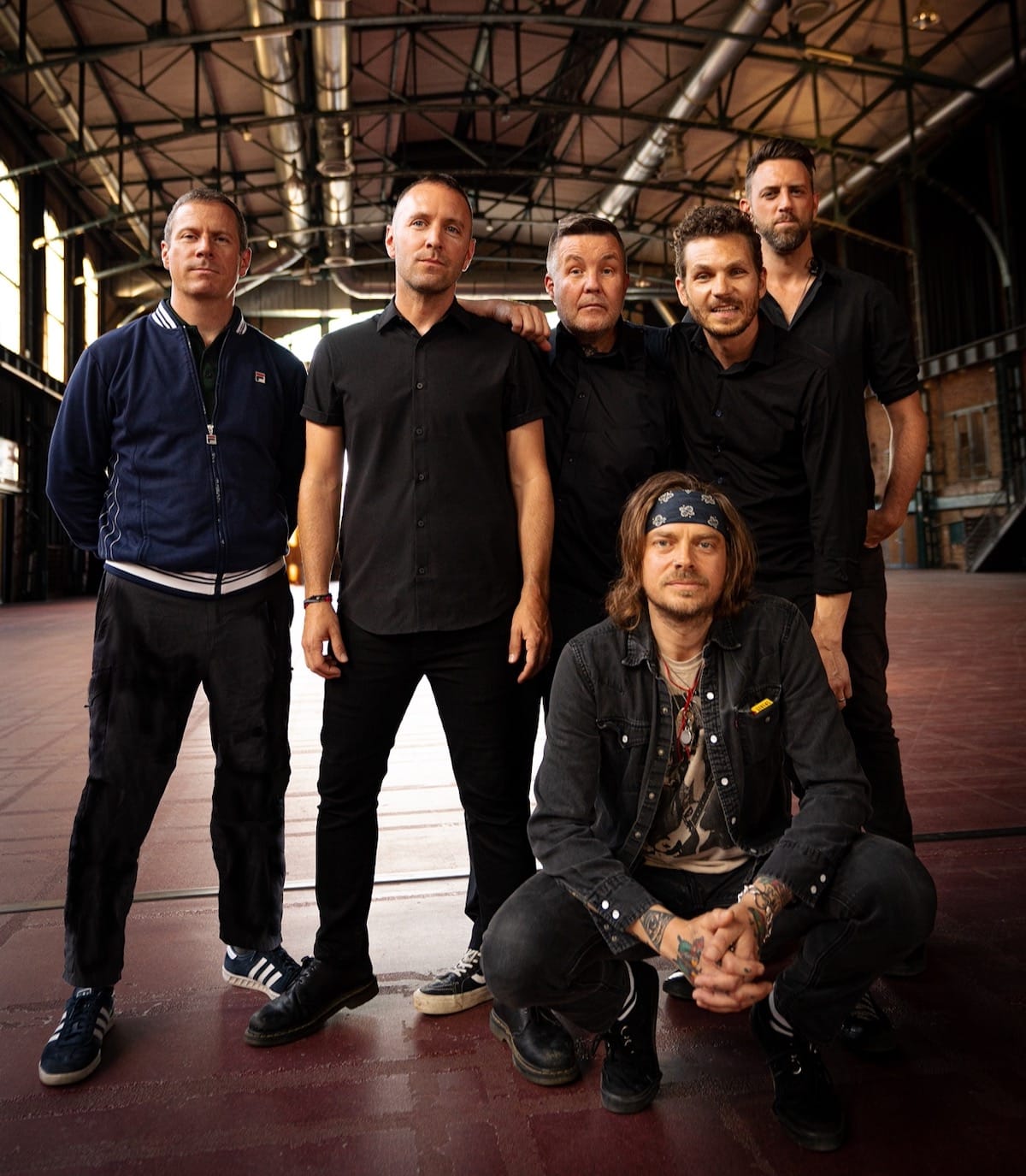 The six members of Dropkick Murphys wearing all black in a warehouse