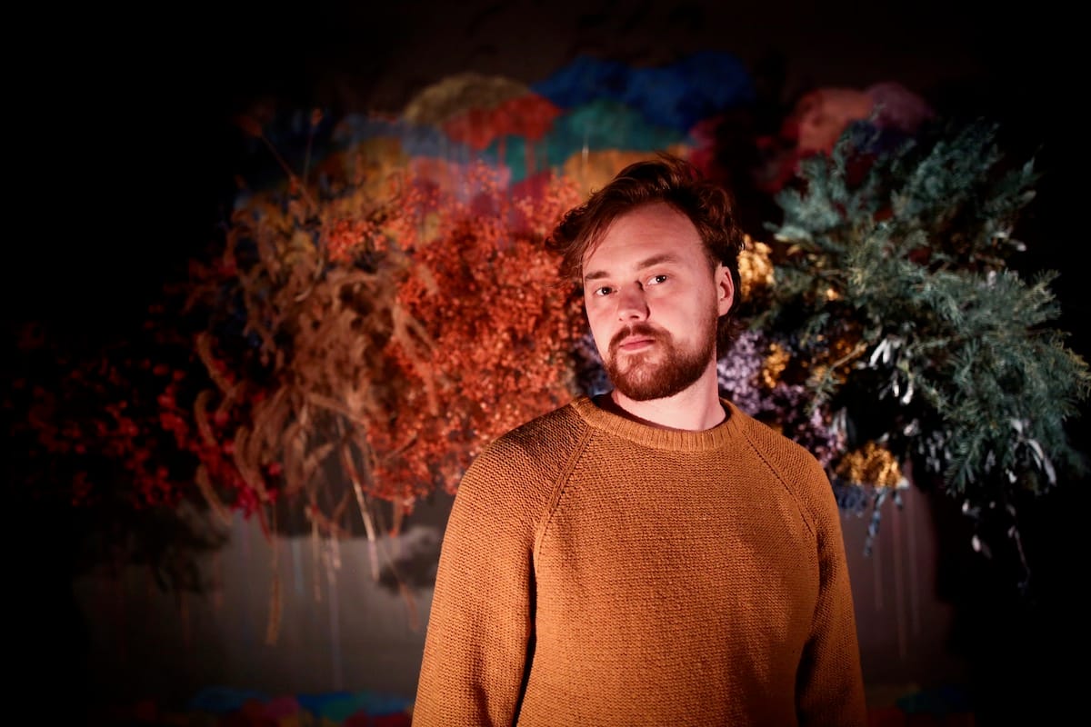 Parker Millsap in orange sweater against a backdrop of fall leaves