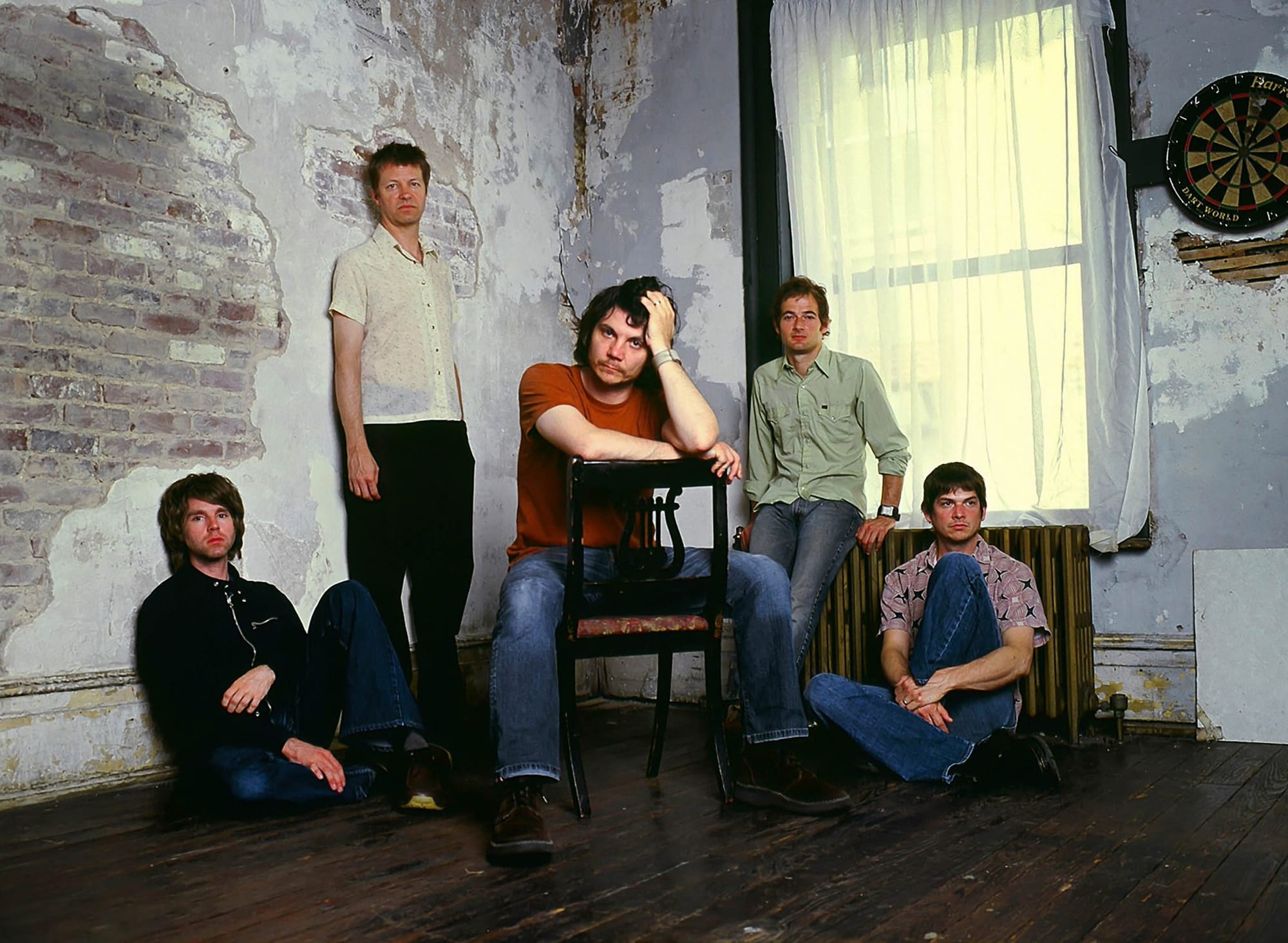 A early photo of the five members of Wilco in the corner of a shabby room