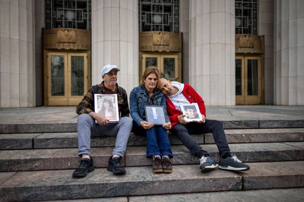 People hold photos of their children outside the Los Angeles Superior Court on February 11, 2026 in Los Angeles, California. 