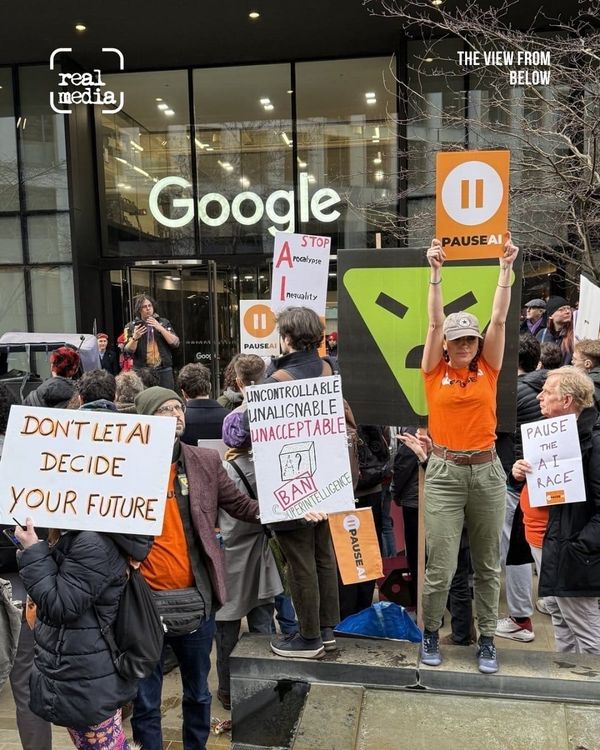 A crowd protests outside a Google office holding signs about artificial intelligence.