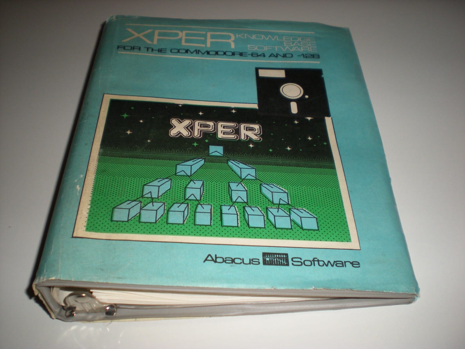 The front cover of the XPER manual, titled “XPER Knowledge Base Software for the Commodore 64 and 128,” showing a stylized tree of connected blocks beneath the XPER logo, with Abacus Software branding at the bottom.