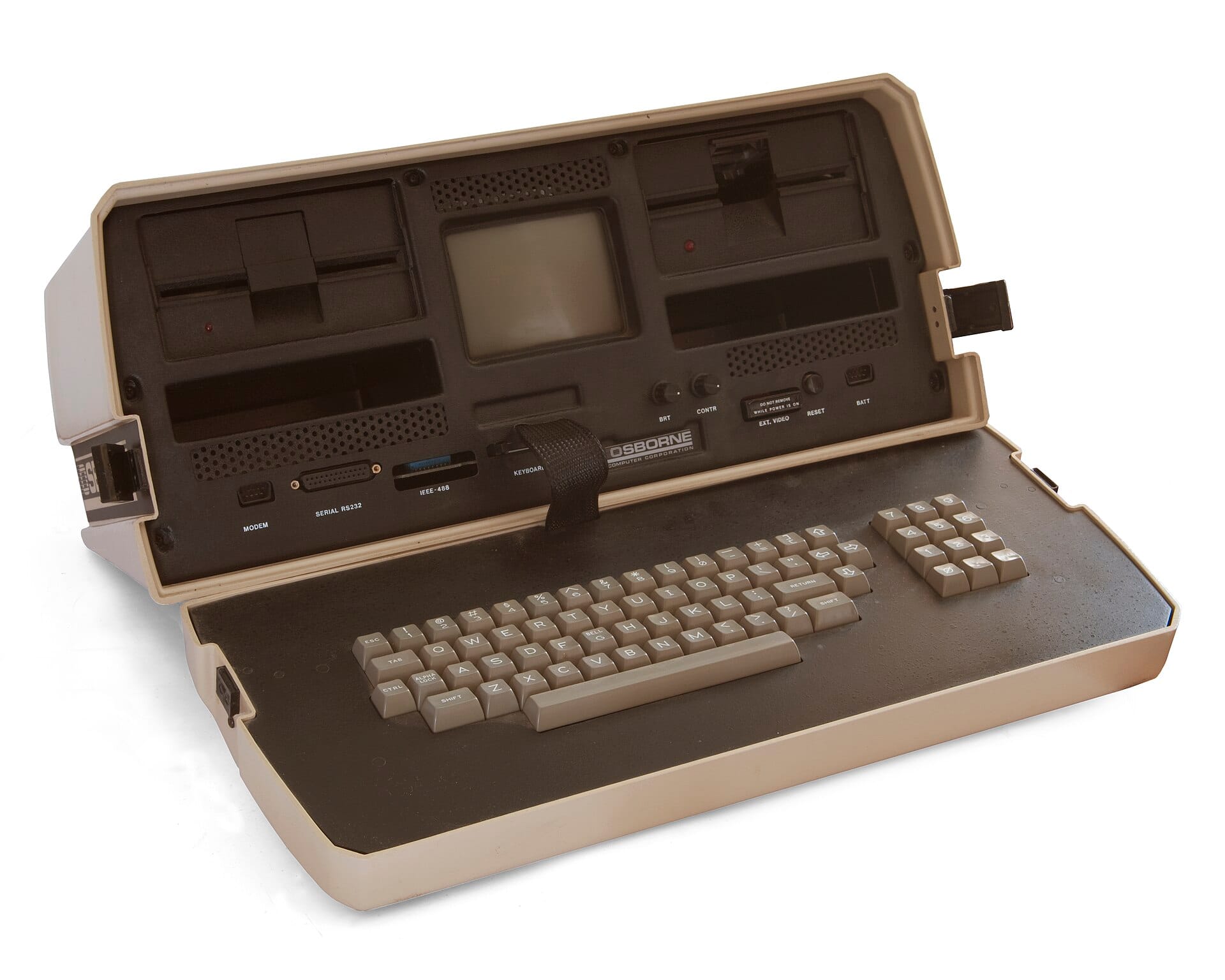 Osborne 1 portable computer with its case open, showing a small 5-inch monochrome CRT centered between two 5.25-inch floppy drives. The detachable keyboard sits in front, connected by a rugged ribbon cable. It is light tan on the outside, chocolate brown inside, tan keyboard. It looks rugged and industrial, and means business.