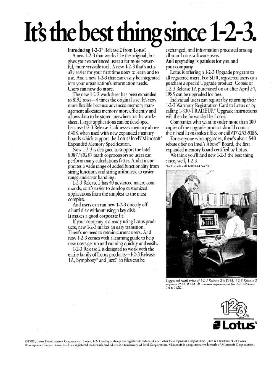 A full-page print advertisement from Lotus Development Corporation, dated 1985, introducing Lotus 1-2-3 Release 2. Not nearly as charming as the first ad; just serious and straightlaced. The headline reads "It's the best thing since 1-2-3." Body copy describes the upgrade's new features: an expanded worksheet of 8192 rows, support for memory above 640K via the Lotus/Intel/Microsoft Expanded Memory Specification, Intel 8087/80287 math coprocessor support, 40 advanced macro commands, hard disk support without a key disk, and compatibility with other Lotus products including Symphony and Jazz. The ad also details upgrade pricing — $150 for registered users, free for copies purchased on or after April 24, 1985 — and includes phone numbers for ordering. A black-and-white photograph shows two men in business attire, one standing and one seated, looking at an IBM PC in an office setting. The Lotus 1-2-3 logo and Lotus corporate logo appear at the bottom right. A footnote gives the suggested retail price of $495 and minimum RAM requirements.