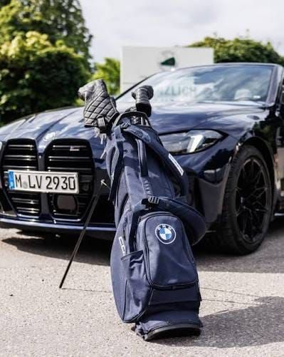 A BMW with a BMW-branded golf bag beside it