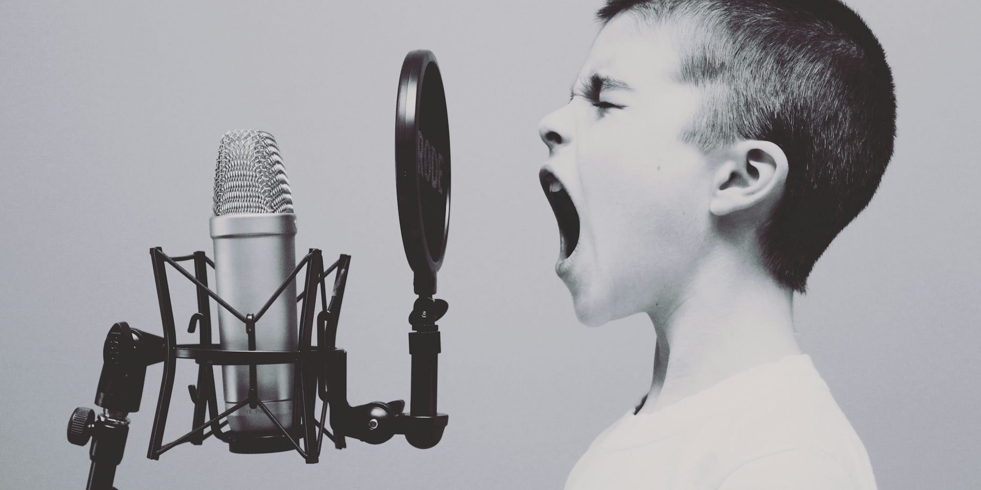 boy singing on microphone with pop filter