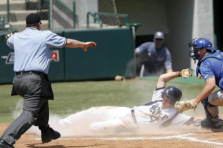 Male baseball player sliding into home plate and is safe.