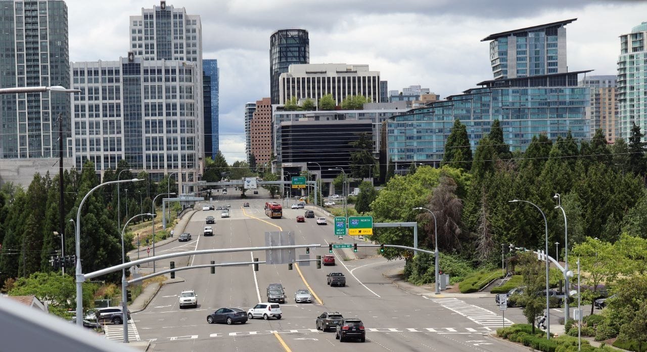 The 8th Avenue overpass incudes eight cars lanes, several slips lanes on the edge of Downtown Seattle with towers in the background. Few pedestrians brave these conditions.