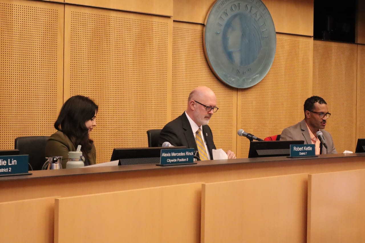 Alexis Mercedes Rinck, Robert Kettle, and Rob Saka sit on the dais.