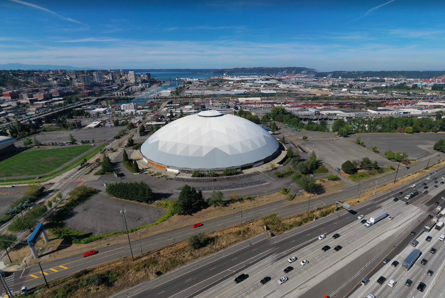 A photo of a dome style stadium surrounded by parking lots near a freeway.