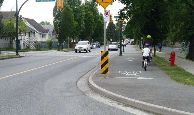 A photo of a bike path on the same level as a sidewalk. 