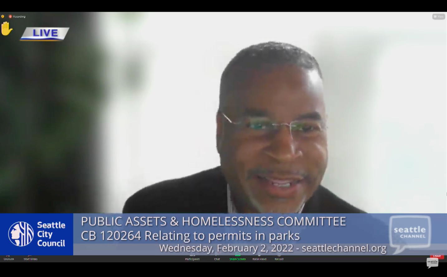 A screen shot of a smiling man wearing glasses speaking a Seattle City Council online meeting.