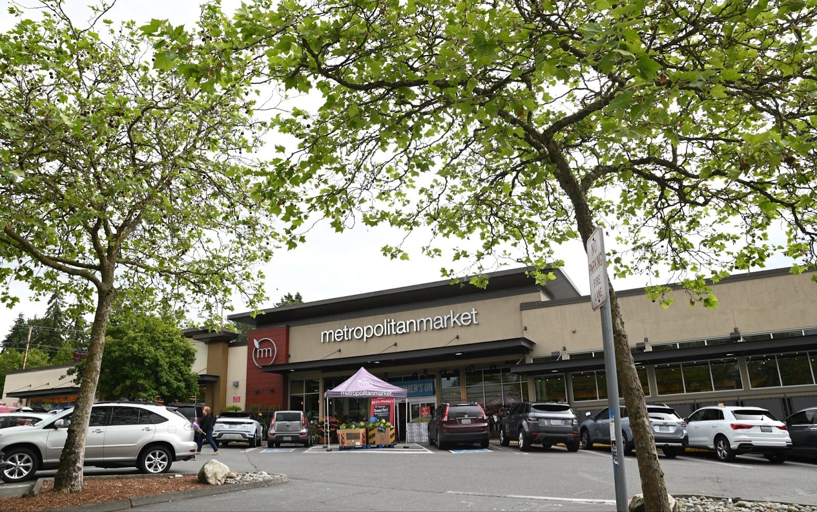 A photo a grocery store with a parking garage and trees.