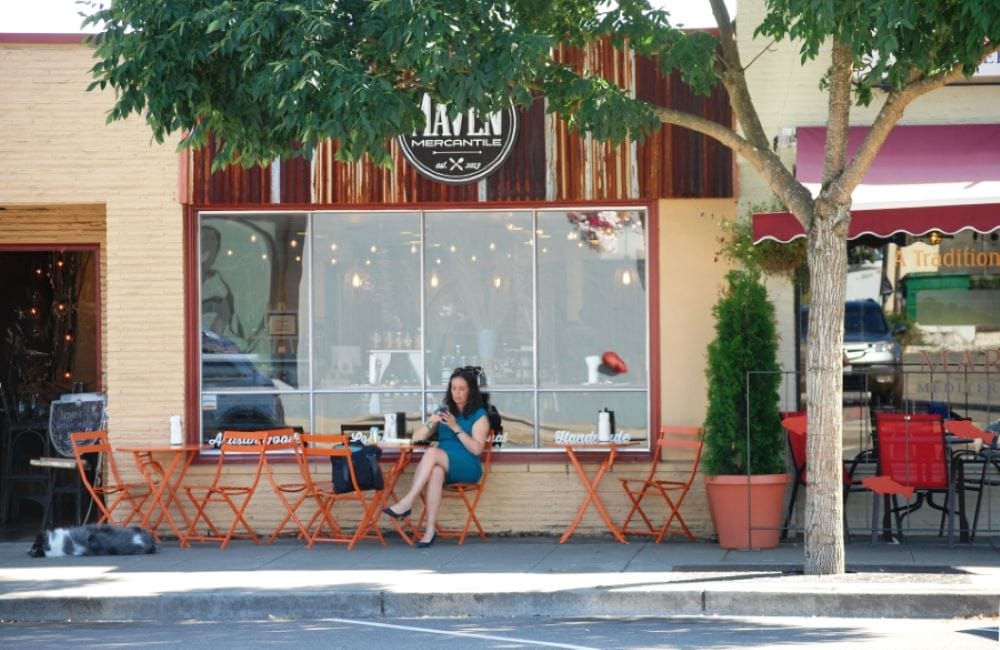 Women sits at a street cafe table outside Maven Mercantile.