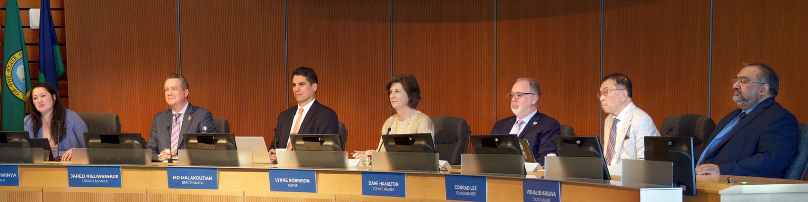 The seven members sit at the Council dais at Bellevue City Hall. From left to right: Claire Sumadiwirya, Jared Nieuwenhuis, Deputy Mayor Mo Malakoutian, Mayor Lynne Robinson, David Hamilton, Conrad Lee, and Vishal Bhargava