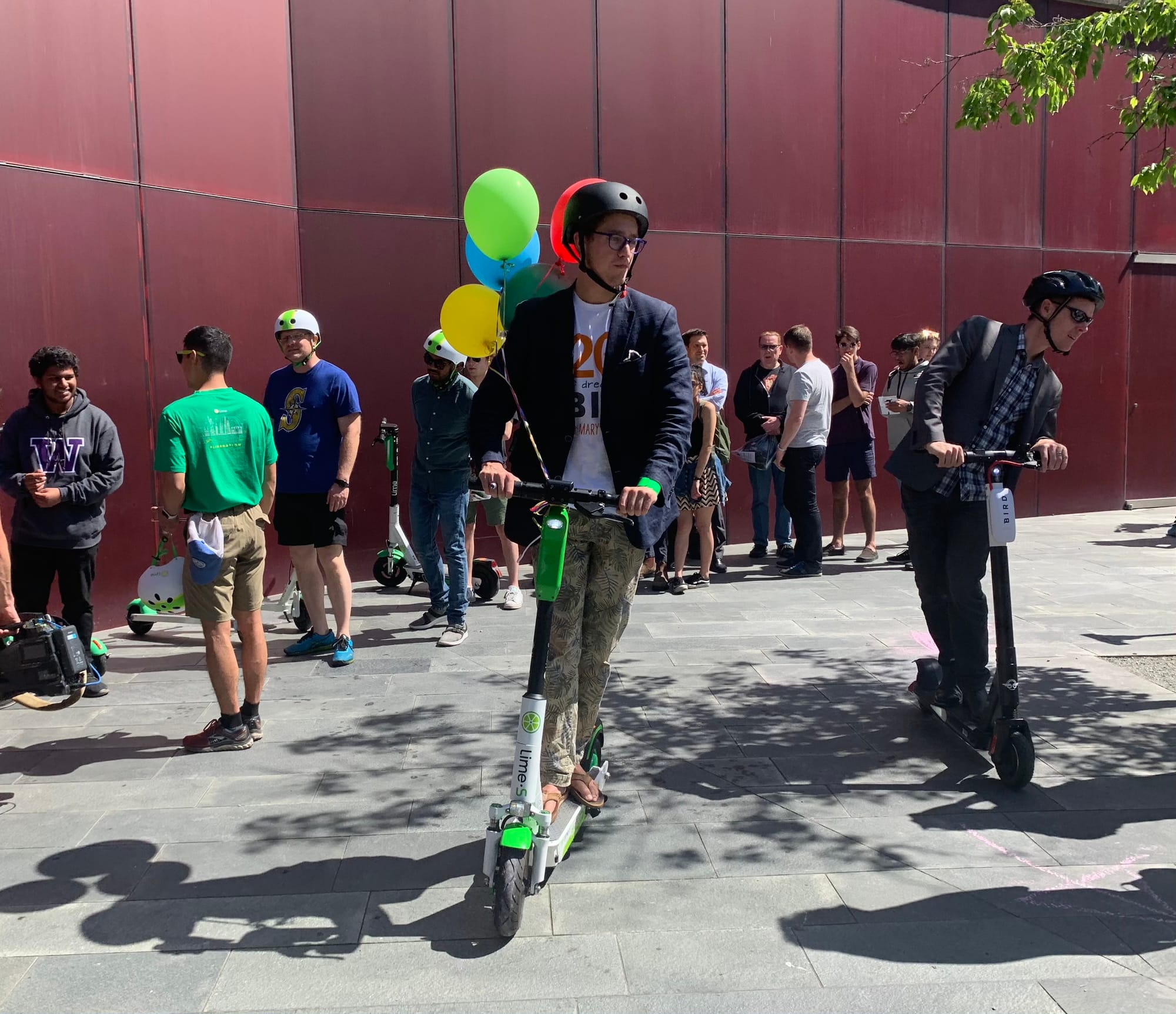 Scooter rider at Seattle City Hall's plaza with a crowd of people milling around