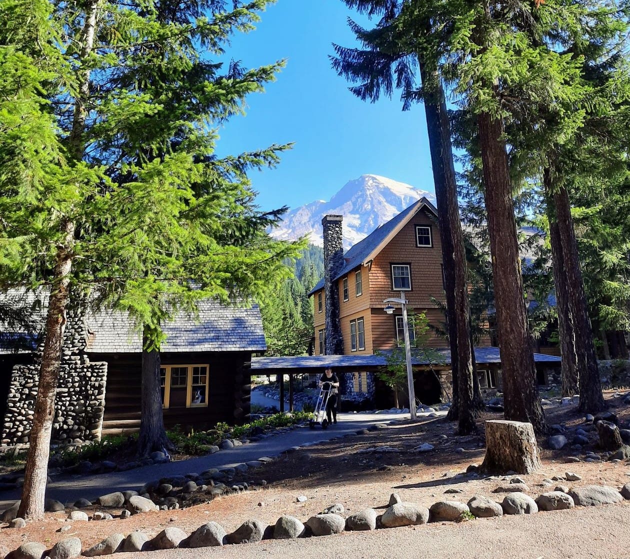 
                     Some Douglas firs and Mount Tahoma frame National Park Inn wooden lodge in Longmire.
                     