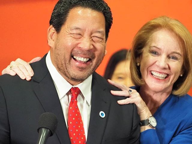 Mayor Durkan gives Bruce Harrell a squeeze on the shoulders.