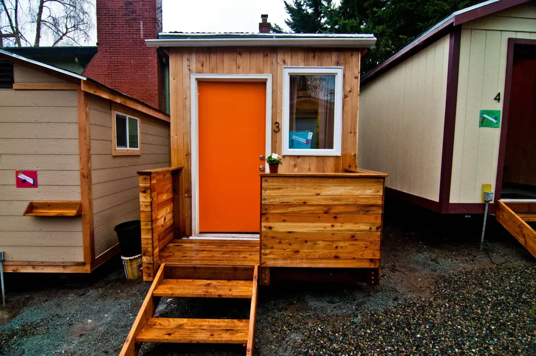 
                     A photo of a tiny house with an orange door.
                     