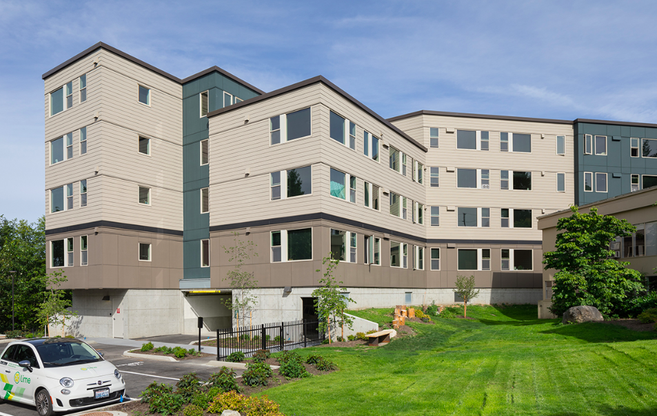 
                     A view of a an apartment building in front of a green lawn.
                     