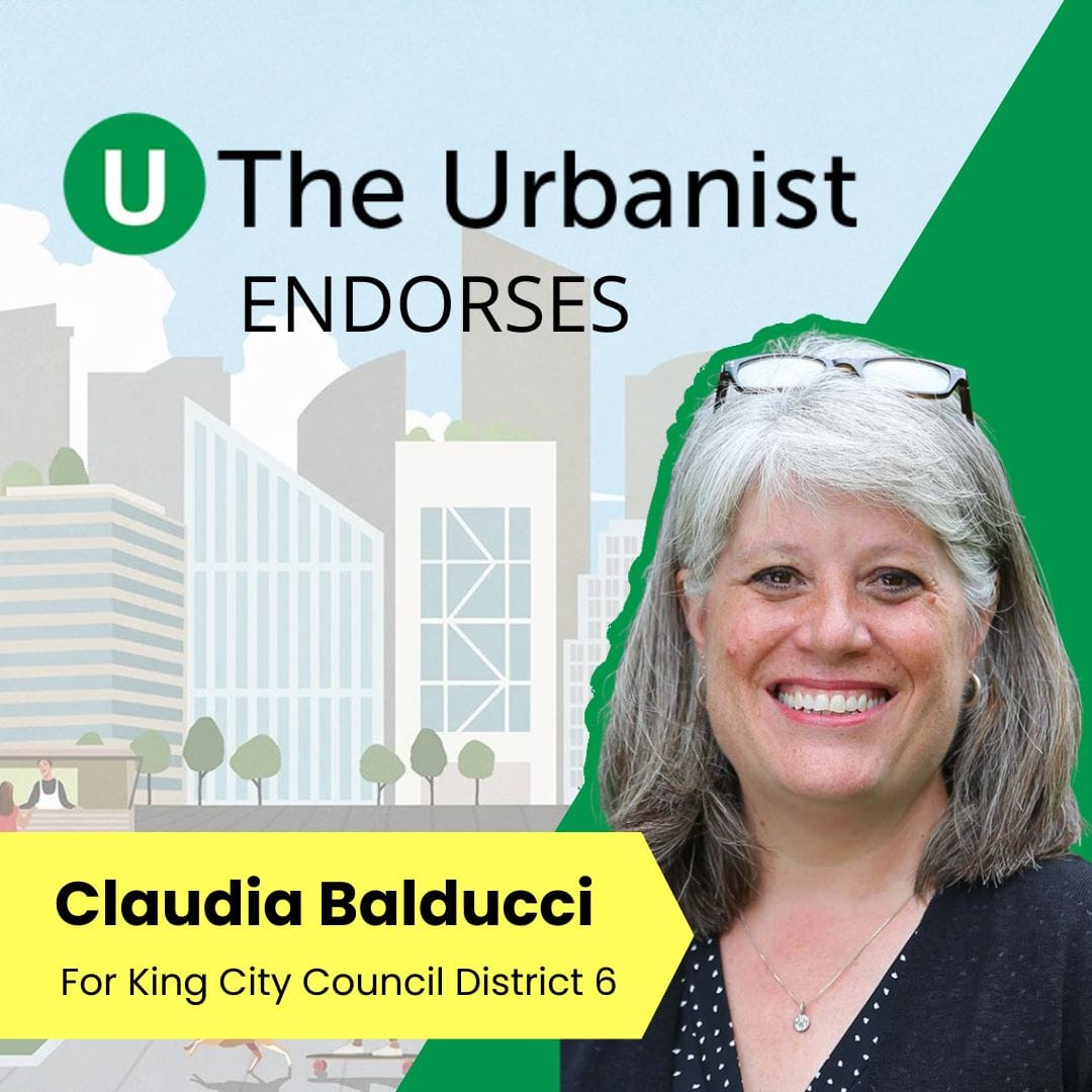 Claudia smiles and has glasses on her head. She is a White woman with gray hair.