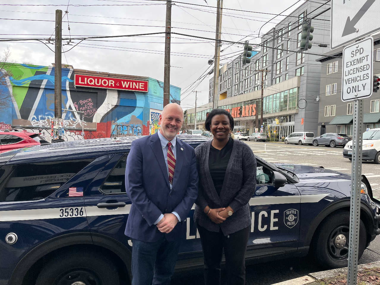 Councilmembers Bob Kettle and Joy Hollingworth pose in front of a police cruiser outside of East Precinct