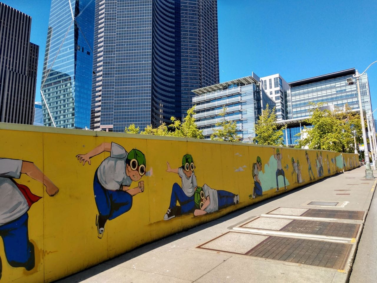 
                     A fence with a pilot boy cartoon figure surrounding Civic Square with Seattle City Hall and the Columbia Tower skyscraper in
                     