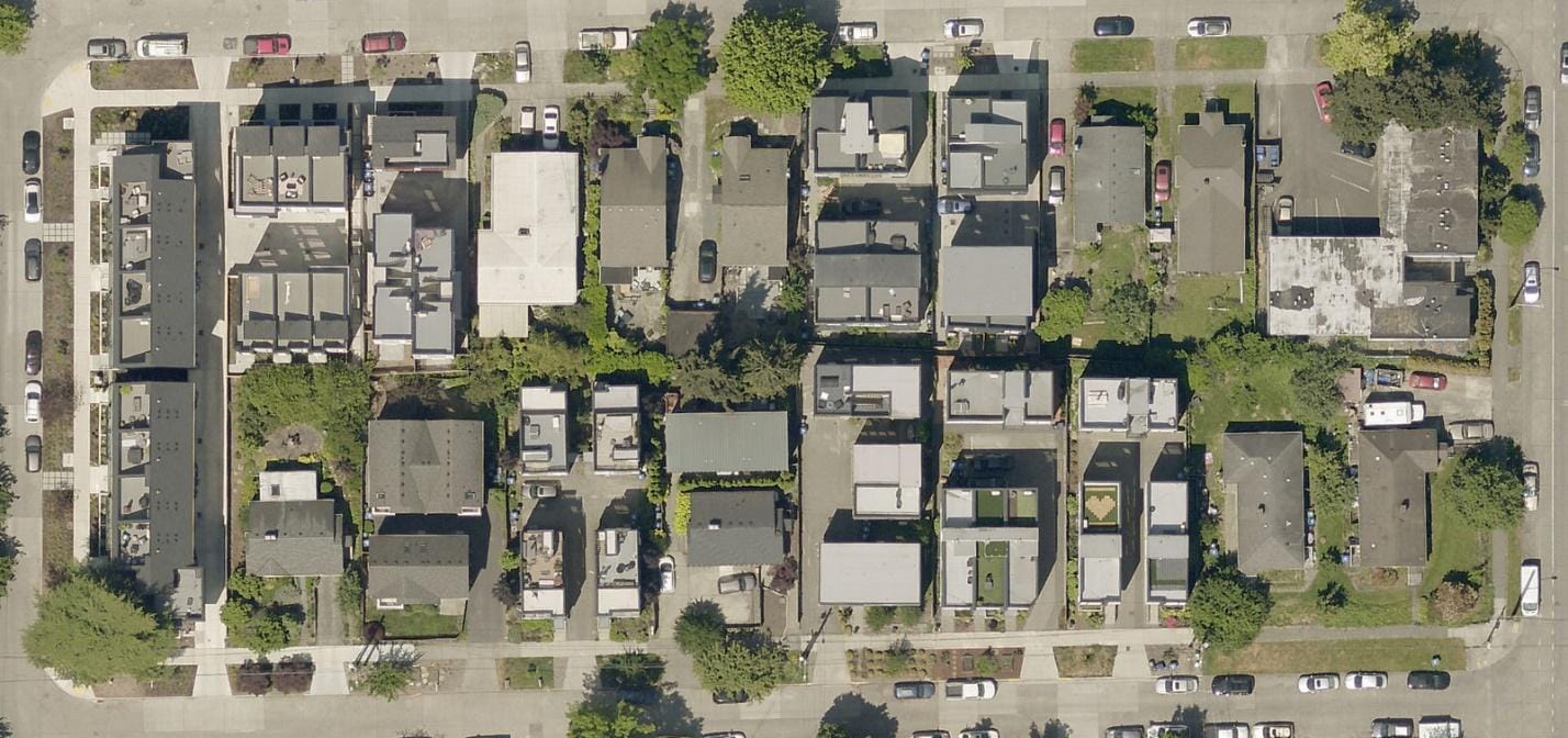 A satellite image shows a block of townhome development. Gray with smatterings of green rather than mostly green.