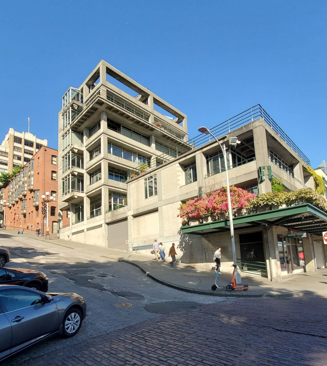 A six-story gray building is built into the steep slope near the Seattle waterfront.