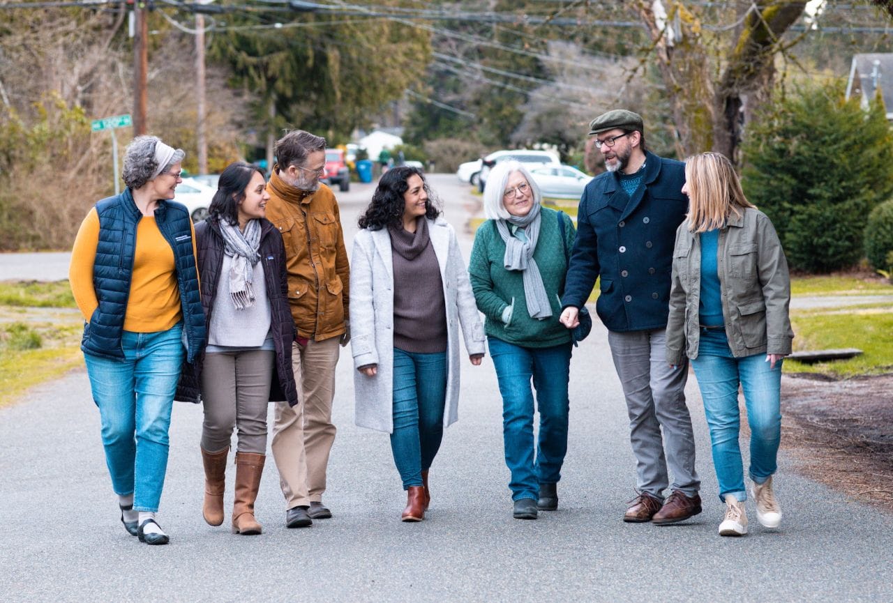 A group of seven walks down the middle of a residential street s with Jenks in the middle.