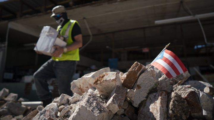 A Puerto Rican flag sits in a pile of rubble after a 6.4 earthquake hit just south of the island on January 7, 2020 in Guáni