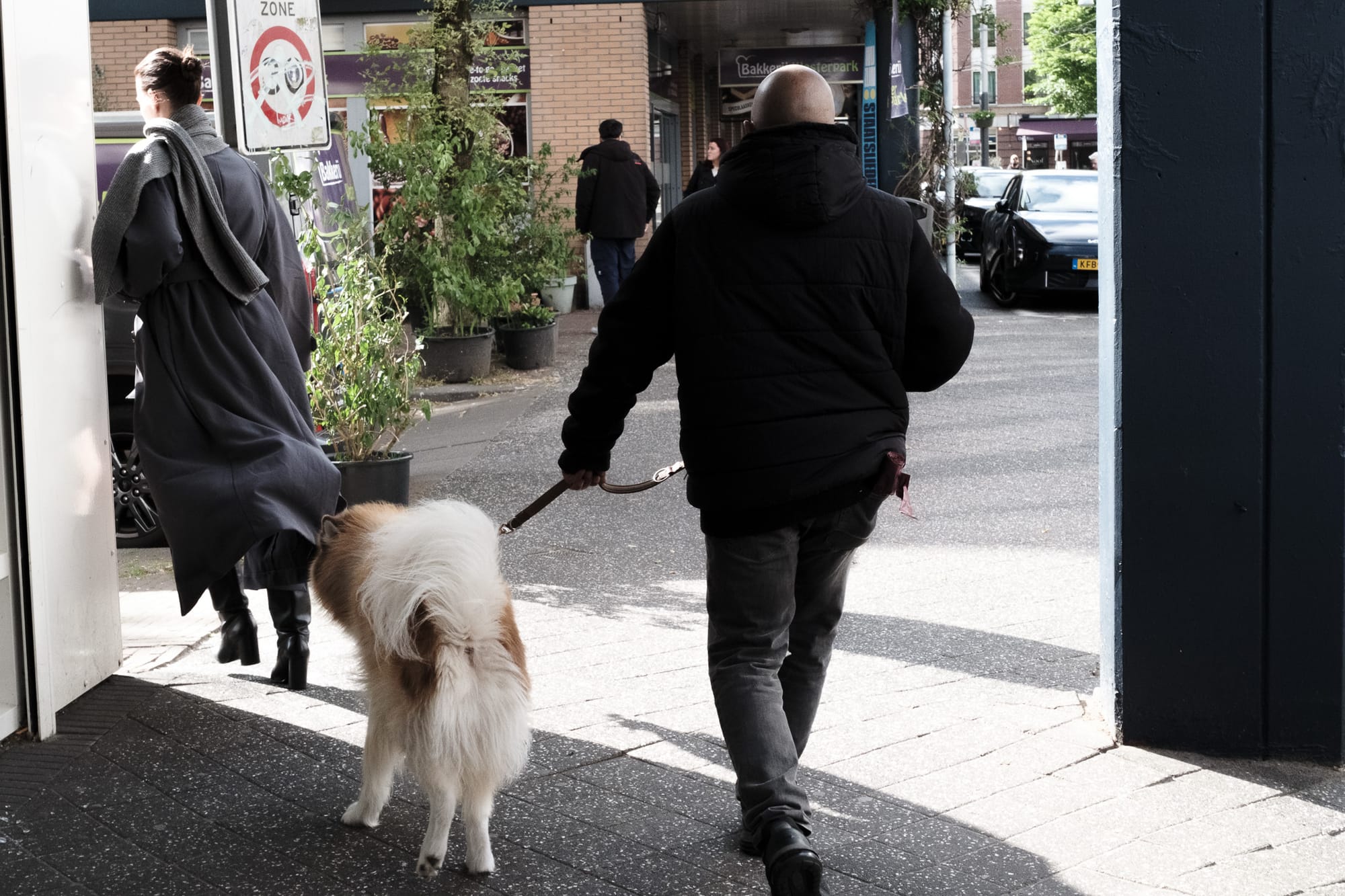 A woman, a dog, a man. Small street photography scene in the streets of Amsterdam