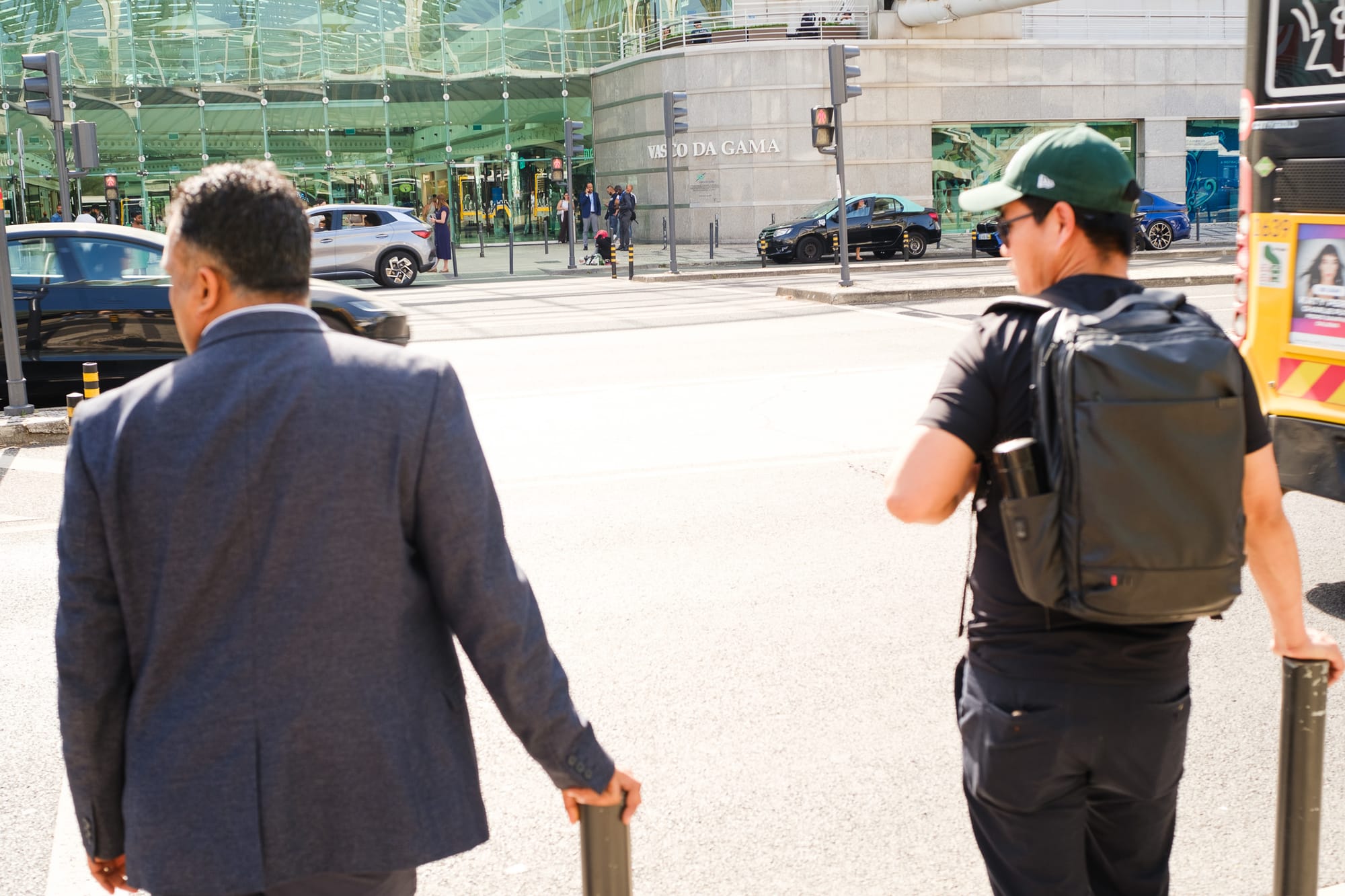 Two men seen from behind walking towards the Vasco da Gama shopping centre in Lisbon on a sunny day