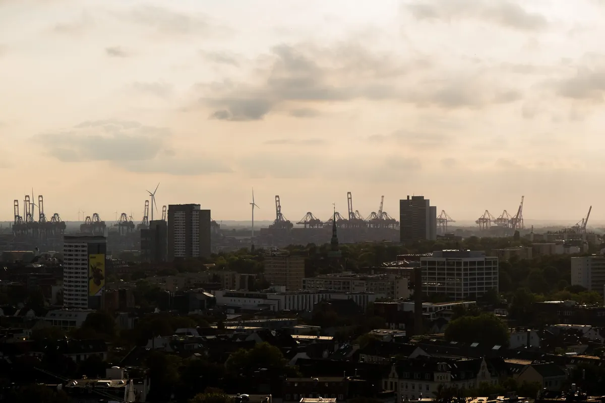 City skyline at dusk with container cranes and wind turbines on the horizon, Germany
