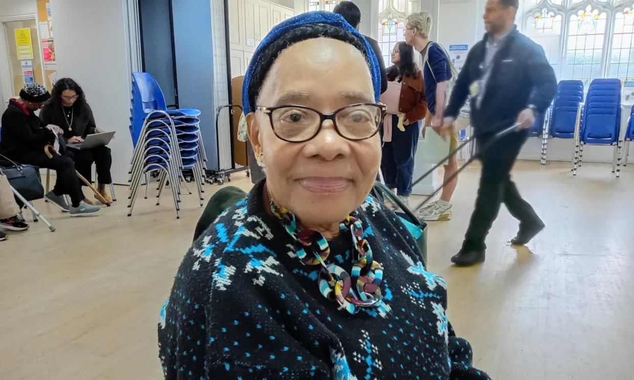 Hazel Watson sits in a town hall room