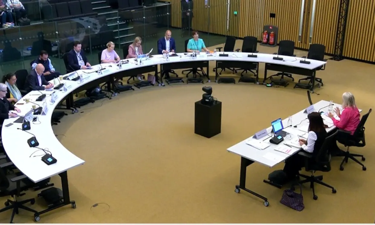 Harpley is presiding over a committee, with members of the GLA Oversight committee sat on a semi-circular desk