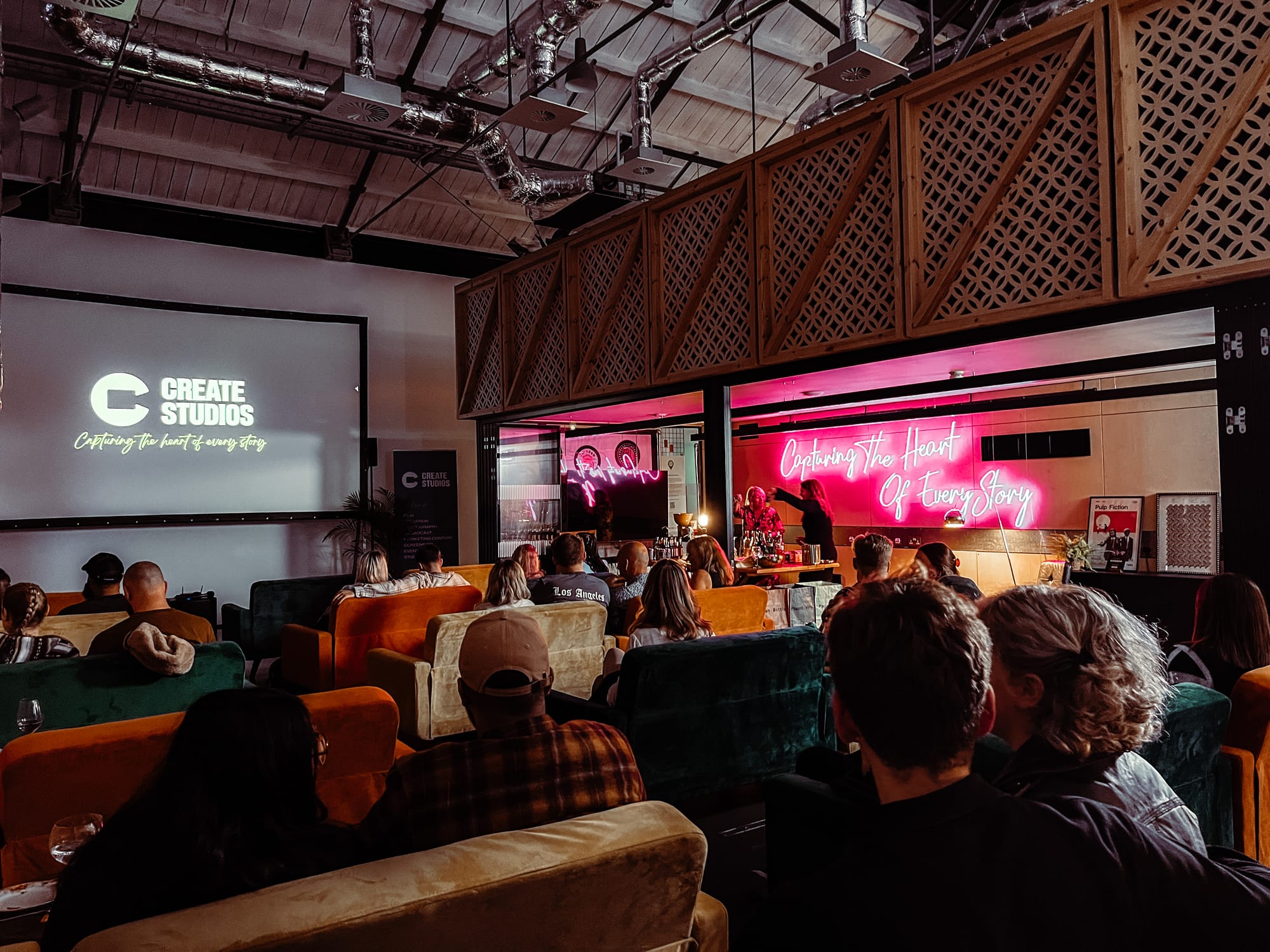 Create Studios' events space. People sitting on sofas watching a screen.