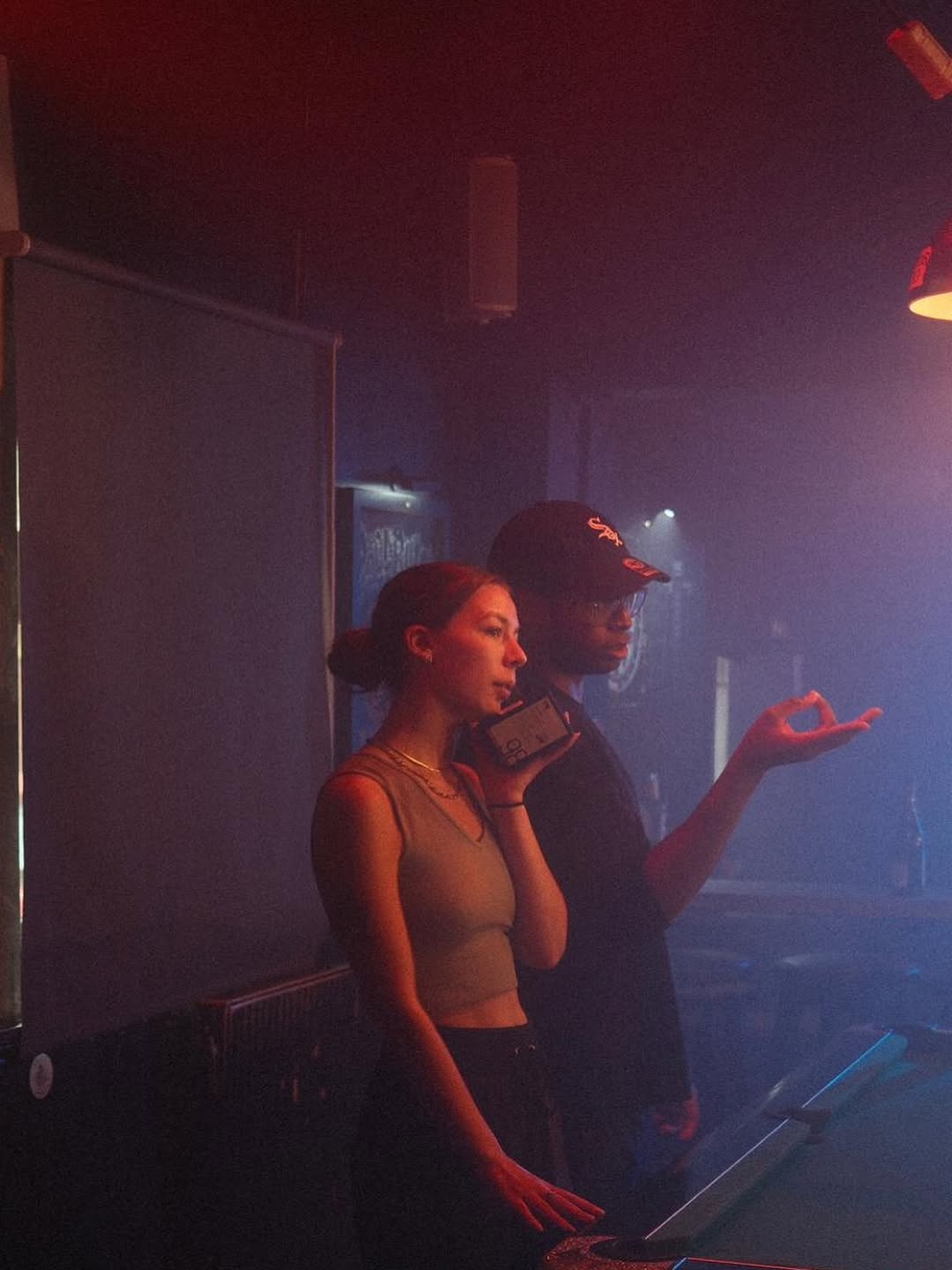Two filmmakers talking whilst on set in a hazy bar.