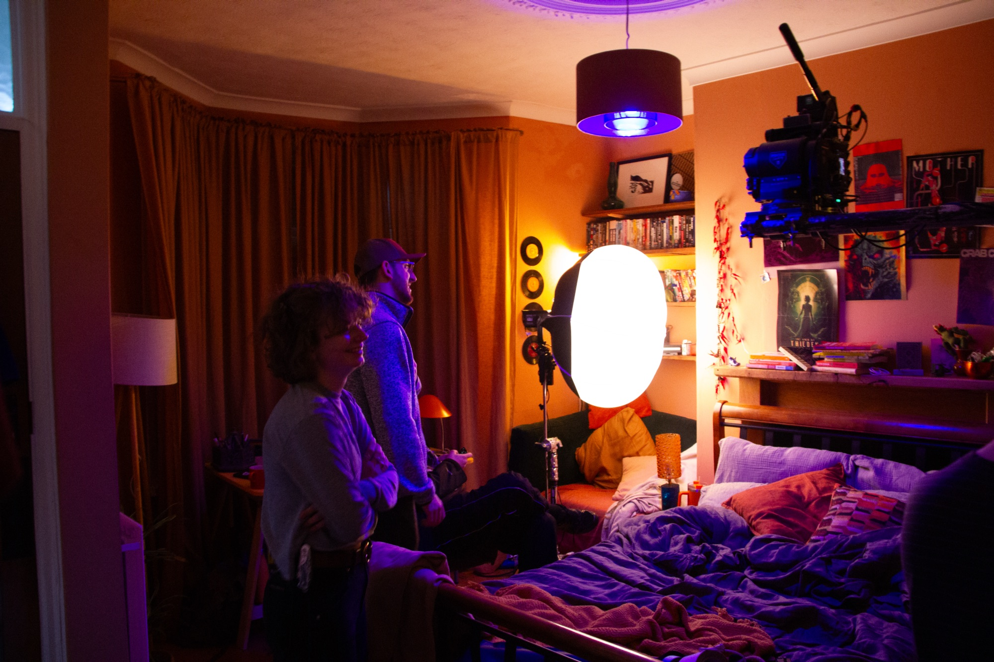 Two filmmakers on a bedroom set.