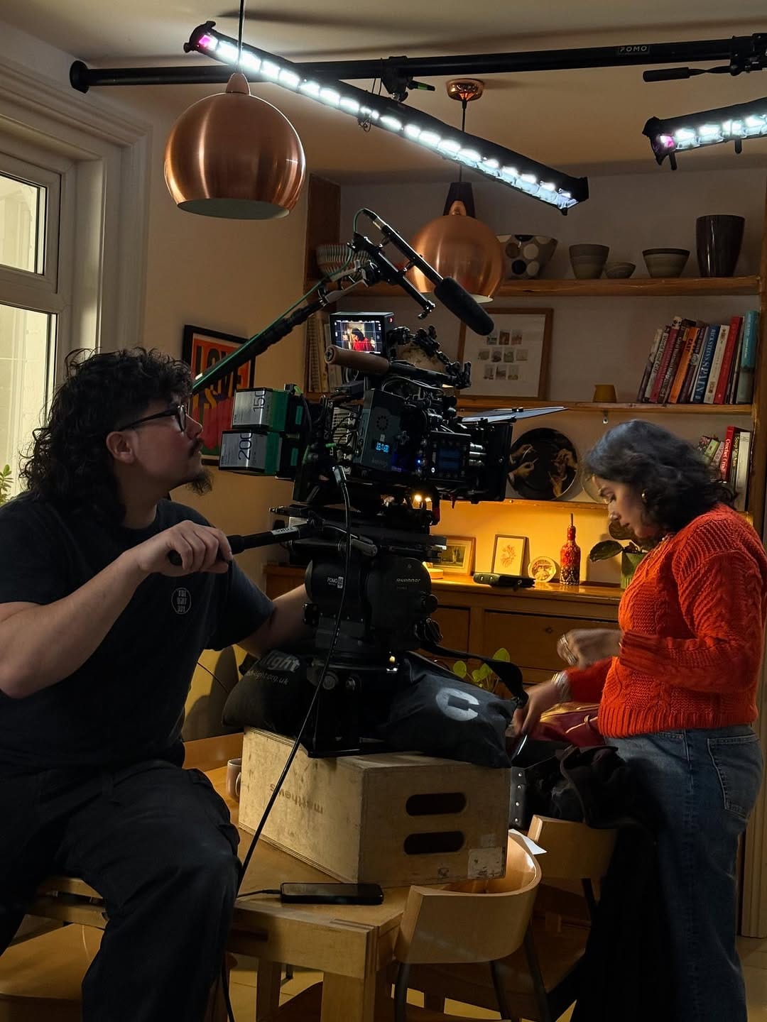 A camera operator films an actor in a dining room location.