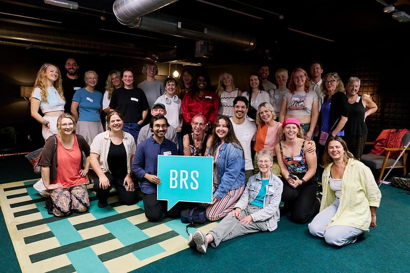 Group posed photo of approximately 30 people with "BRS" sign.