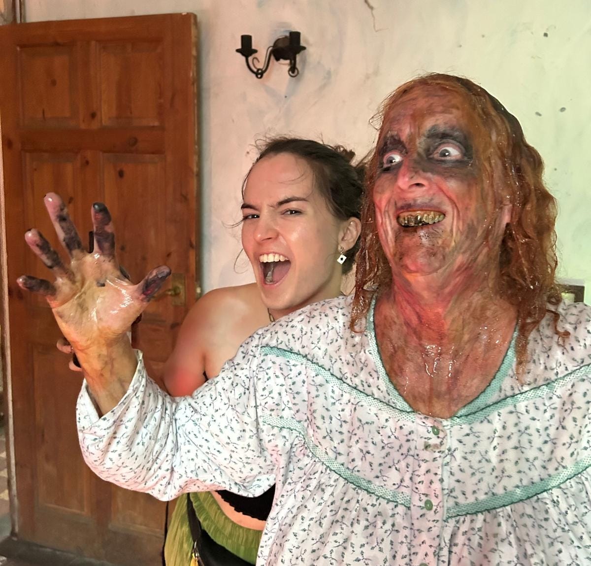 An actor in full horror make-up beside the Make-Up Artist who is smiling.