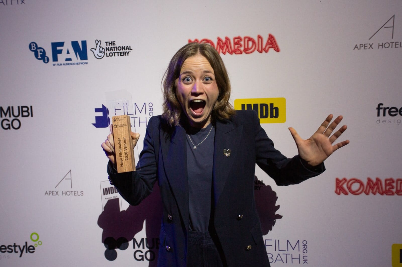 Filmmaker screaming with excitement with their award in front of a Film Bath banner.