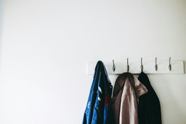 Coats hanging on wall hooks, symbolising relationship uncertainty, decision pressure, and the relief that can follow choosing whether to stay or leave.
