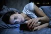 Woman in bed looking at phone.