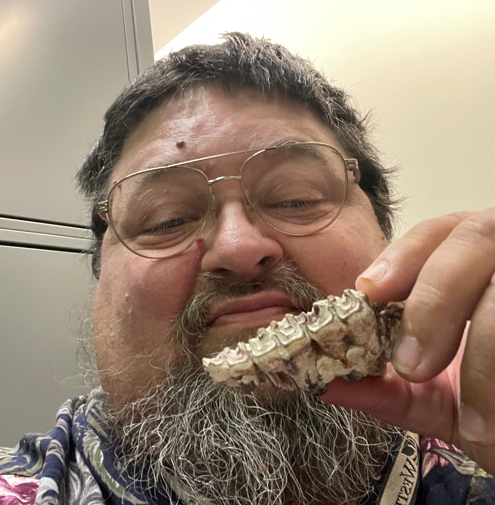 Scientist examining a jaw fragment with three small teeth.