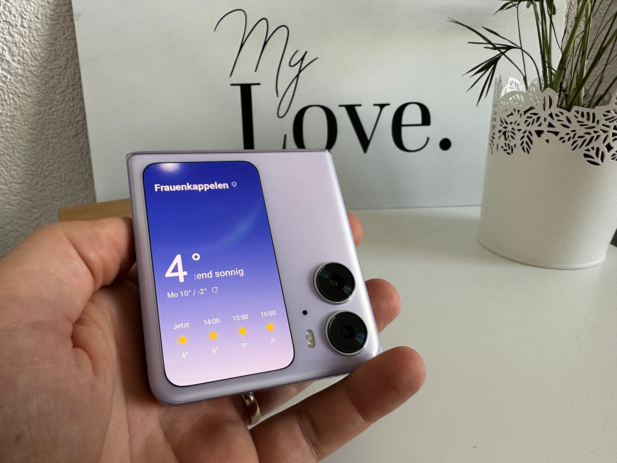 Das Oppo Find N2 Flip in der Farbe violett mit aktiviertem Display. Jemand hält es in der Hand.