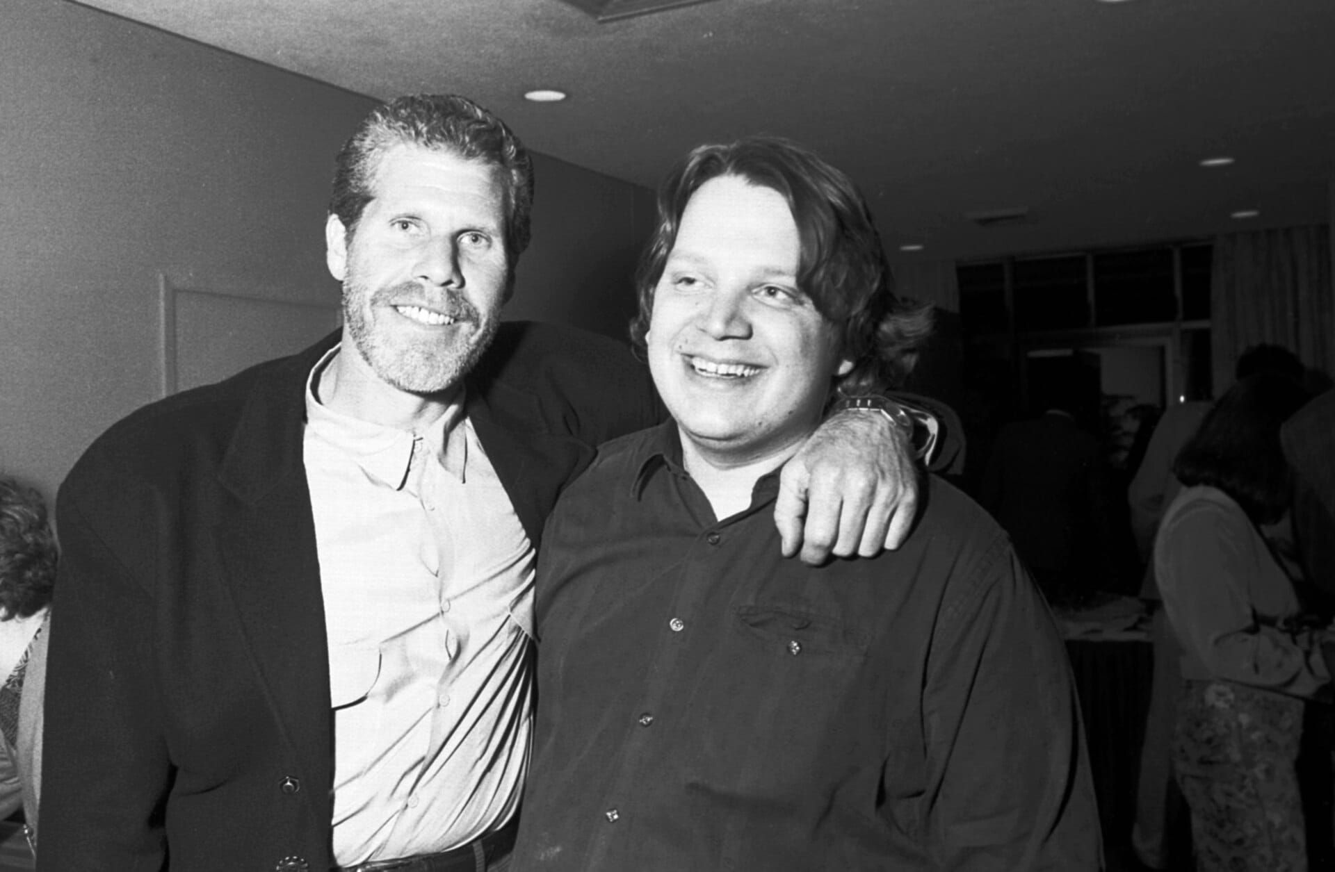 Schwarzweissfoto: Ron Perlman legt den Arm um Regisseur Guillermo del Toro, beide lächeln.