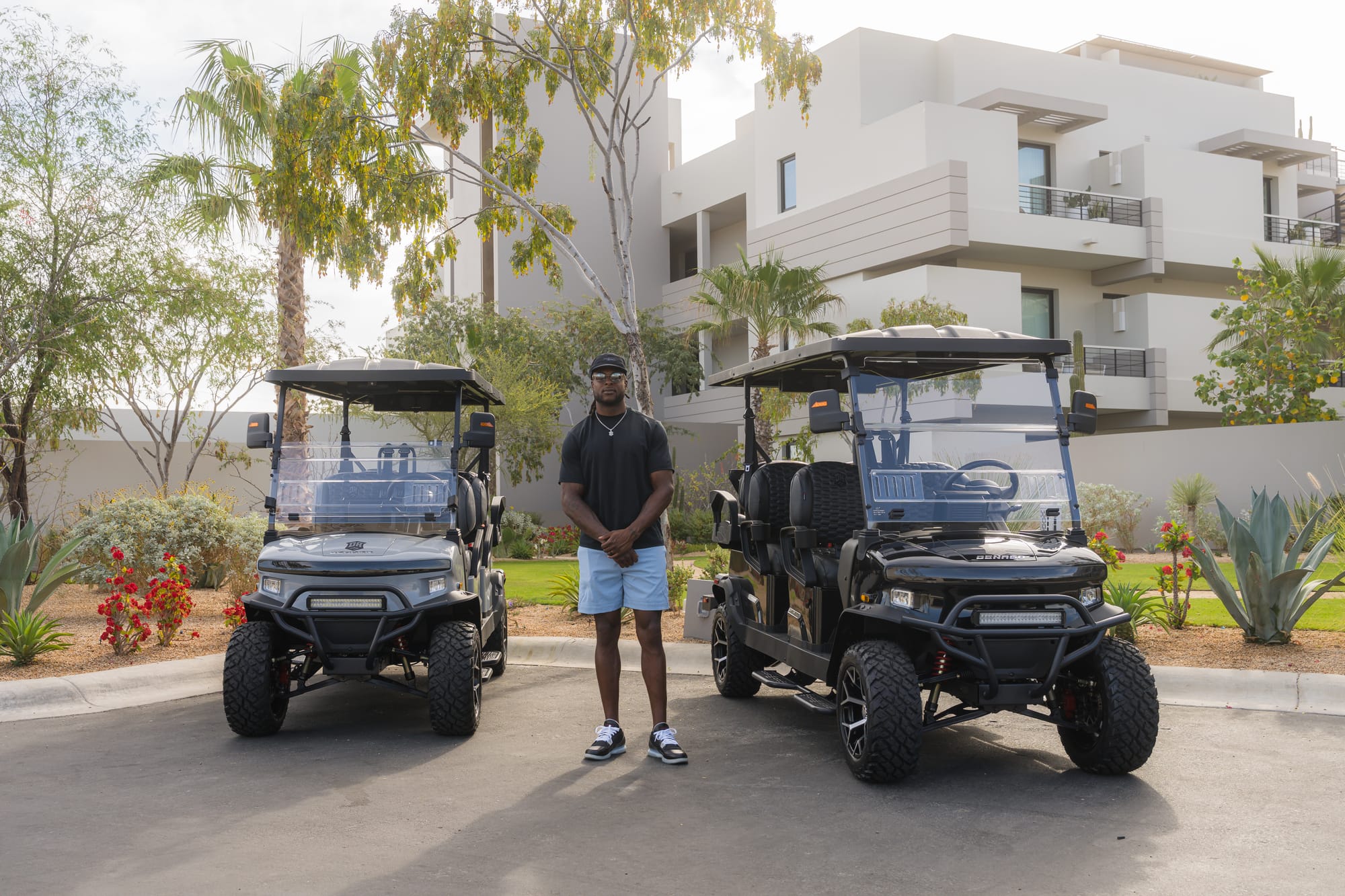 Davante Adams standing between his two new Denago Rover XL6 golf carts